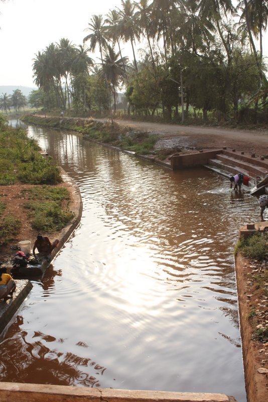 Washing clothes the the brown canal.